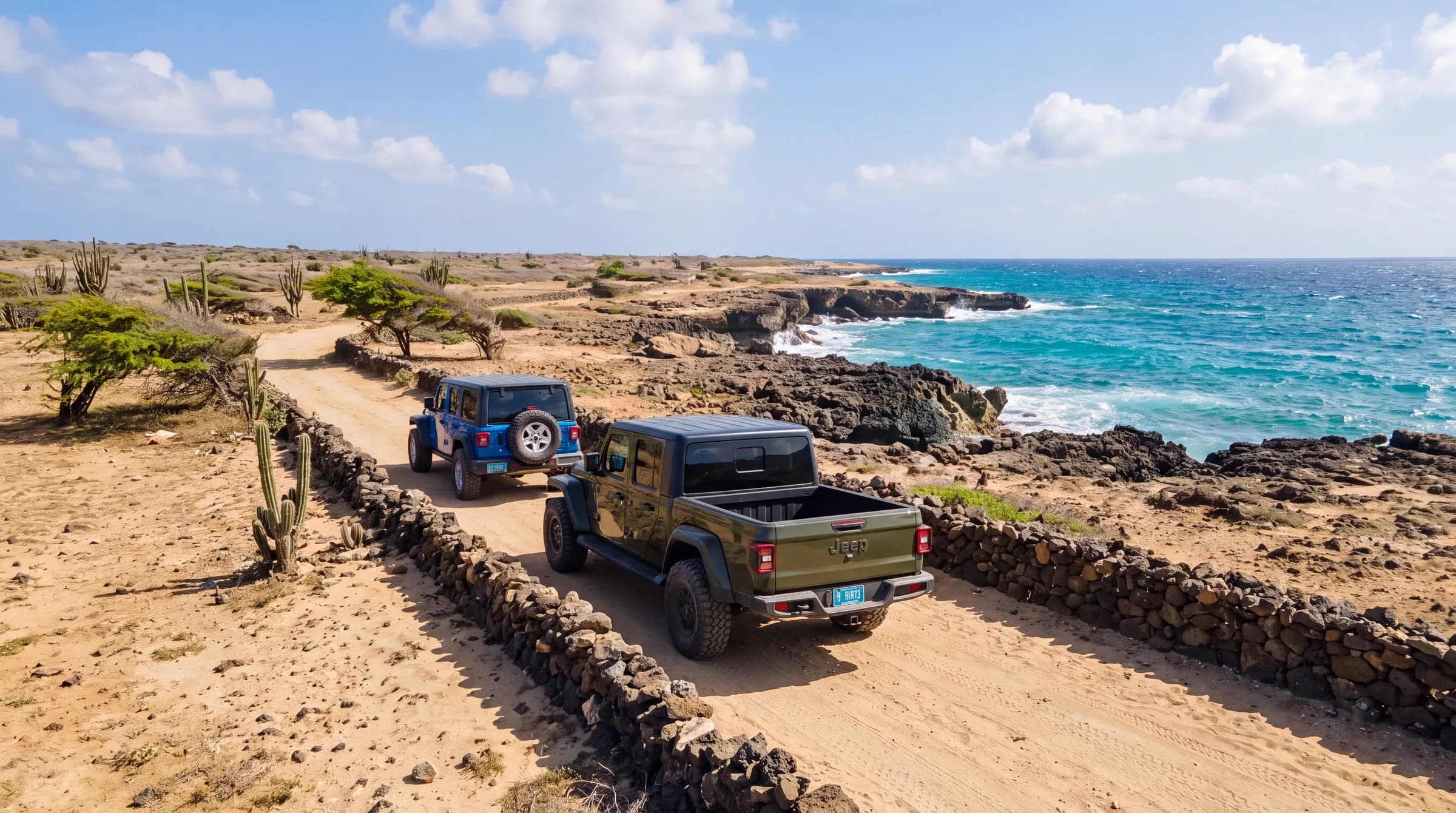 Two Jeeps seen from behind on the stone-walled coastal trail in Aruba