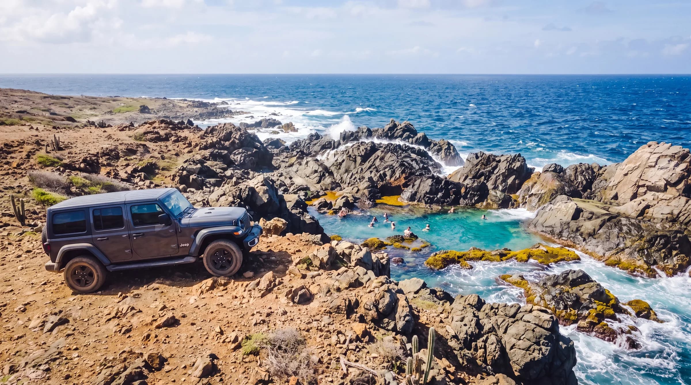 Gray Jeep Wrangler parked at the viewpoint above Conchi, the Natural Pool, on the Aruba north coast